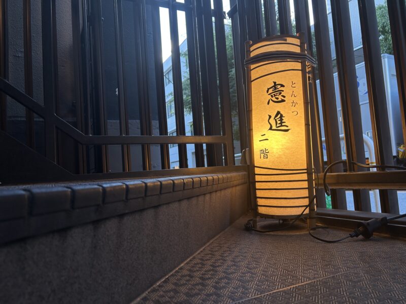 飯田橋「憲進」夕闇に煌々と輝く階段に設置された看板